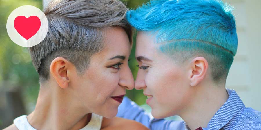Two young lesbian woman with short hair looking intently into each other’s eyes.