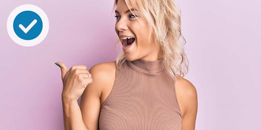 Cute young blonde woman making the thumbs up symbol.