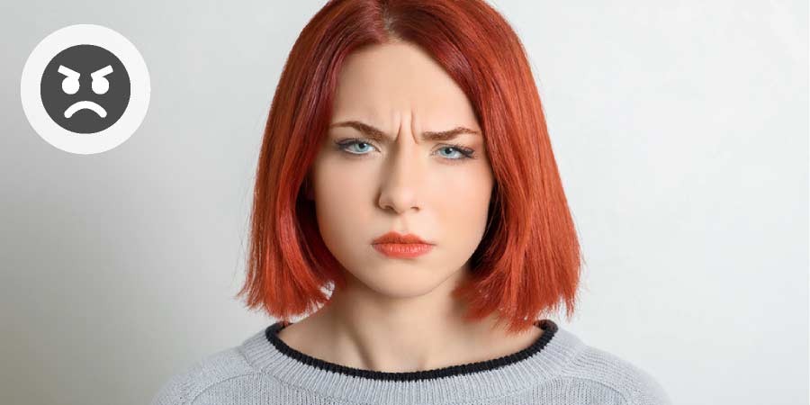 Young woman with red hair scowling.