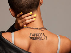 Lesbian with cropped hair and a leather jacket with “express yourself” tattooed on her back