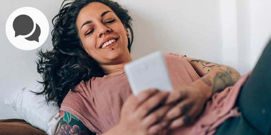 Attractive woman with arm sleeve tattoos using her mobile phone to video chat.